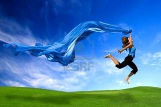 Beautiful athletic woman jumping on a green meadow with a scarf Stock 